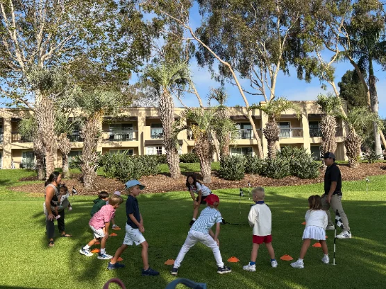 Coaches leading warm-up drills with a group of young players on the lawn