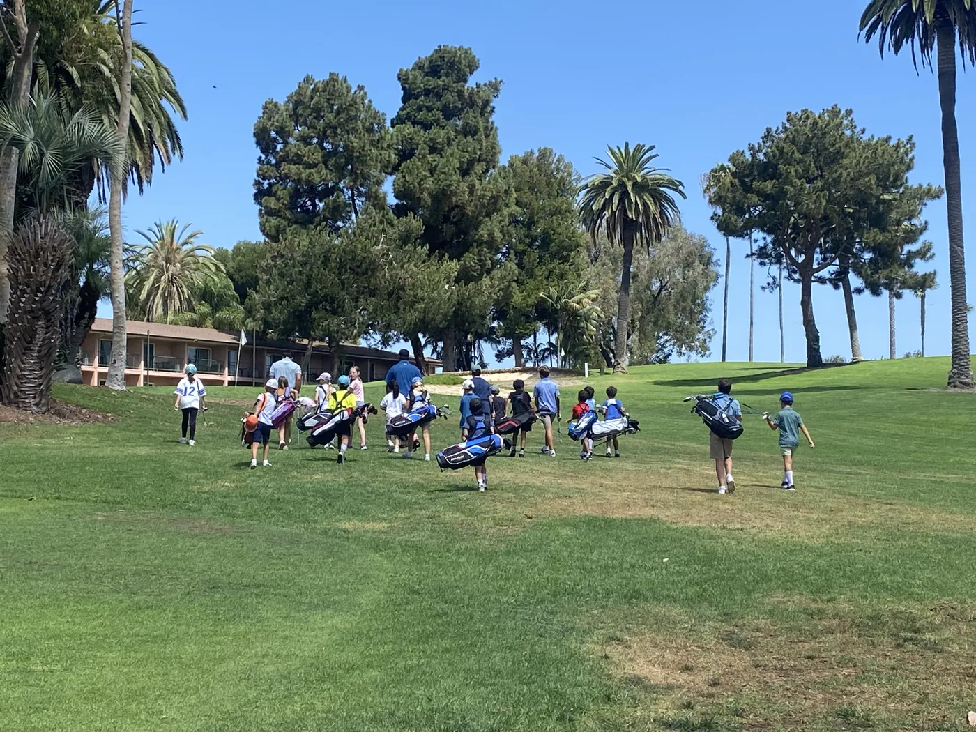 Young players walking the fairway with their golf bags